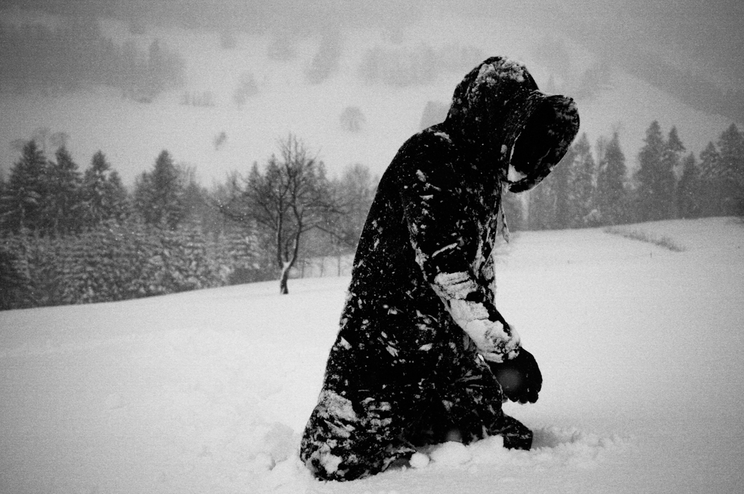 Черные снежки. Человек в снегу. Парень под снегом. Человек в заснеженном поле. Человек под Снегопадом.